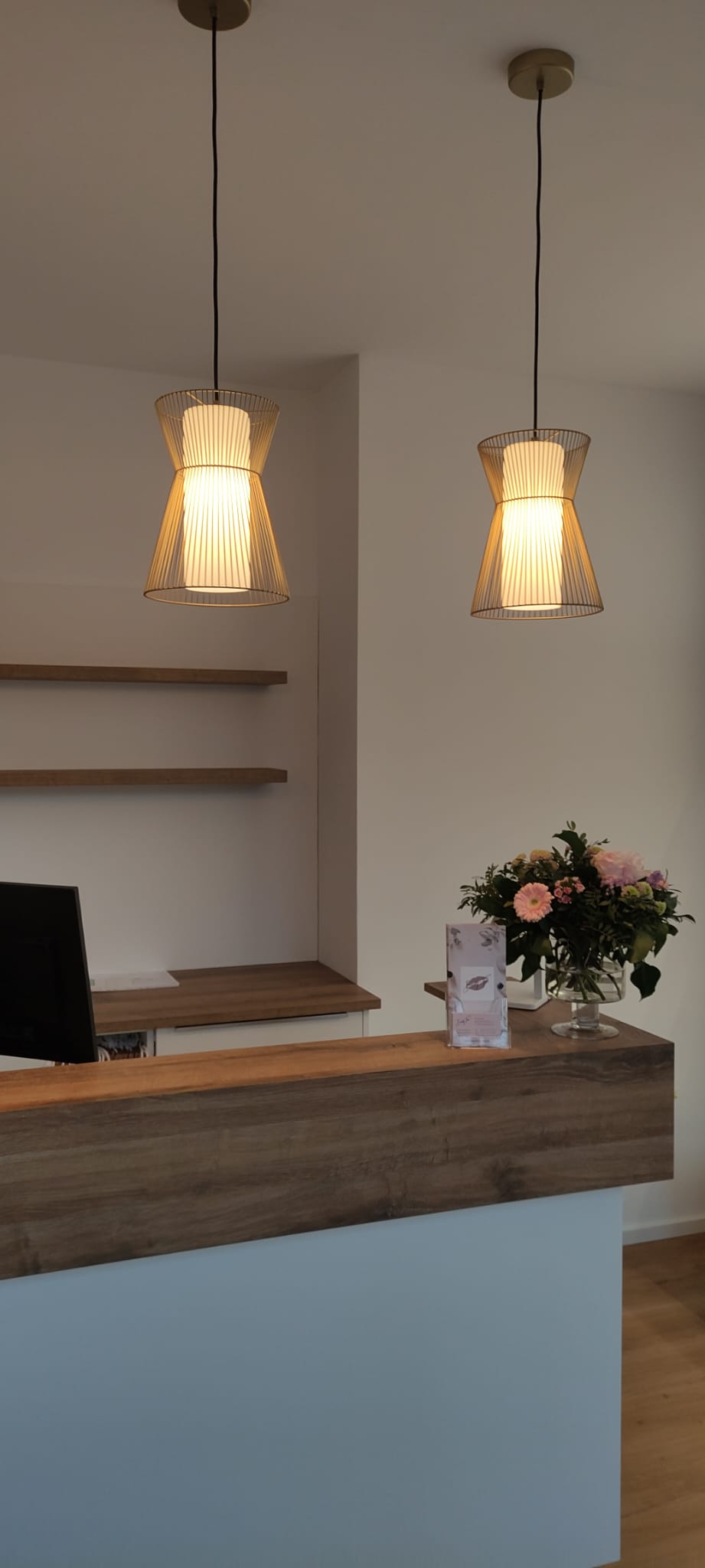 Empfangstheke mit Pendelleuchten und Blumen