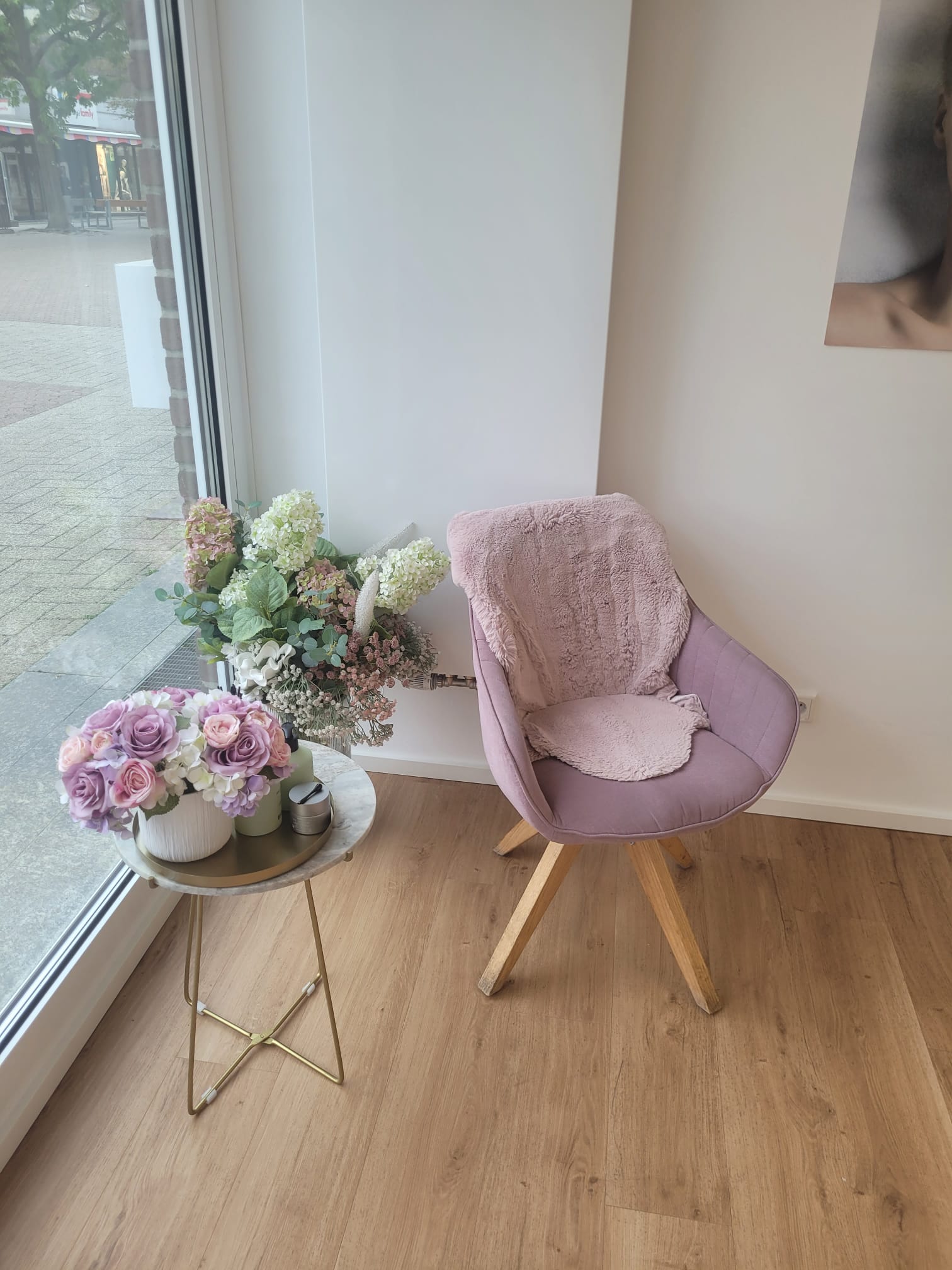 Wartebereich mit rosafarbenem Sessel und Blumen am Schaufenster
